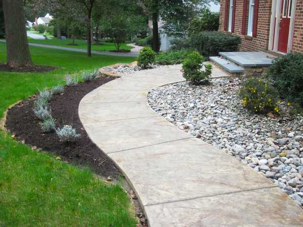 Curved concrete walkway through a landscaped yard